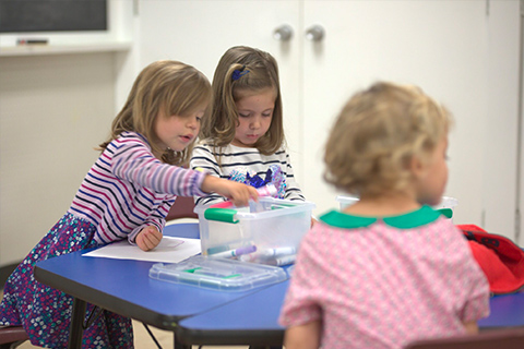 Children colouring together at a table in the classroom