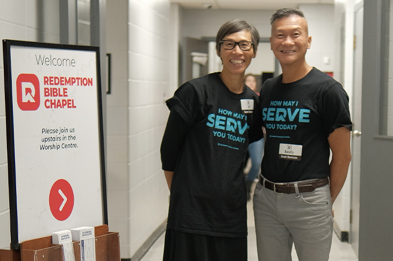 Two greeters standing and smiling