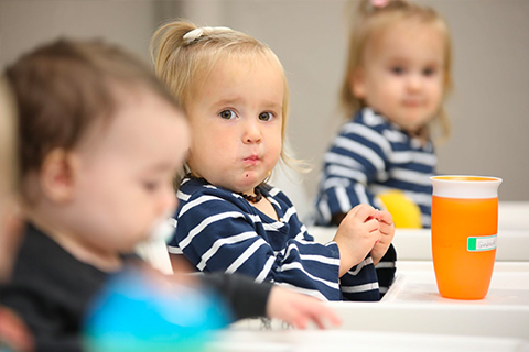 Toddlers eating snack together in classroom