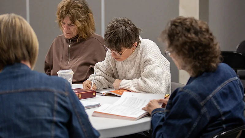 Women sitting around table reading and studying the Bible
