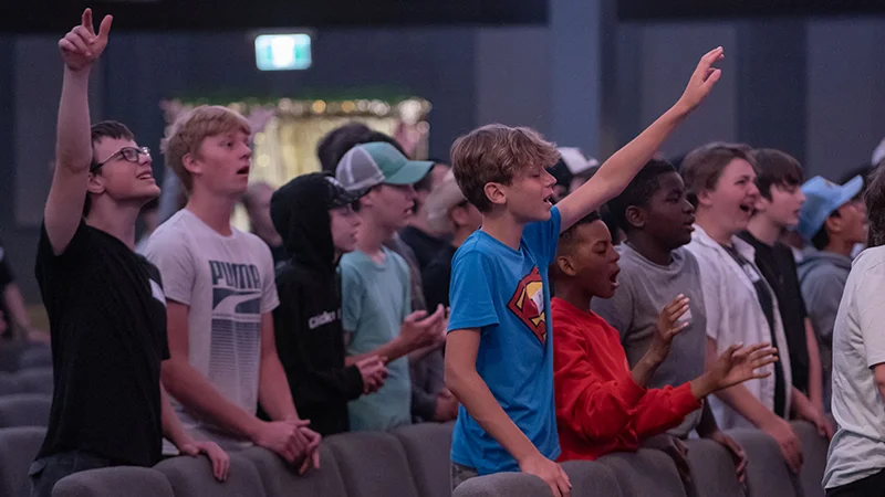 Youth worshipping with hands raised up high