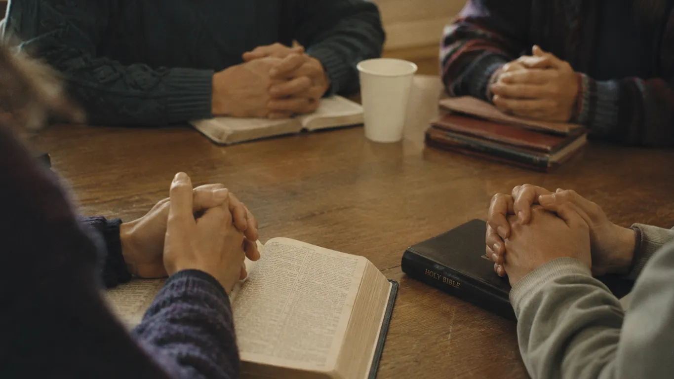 Praying together with hands on Bible