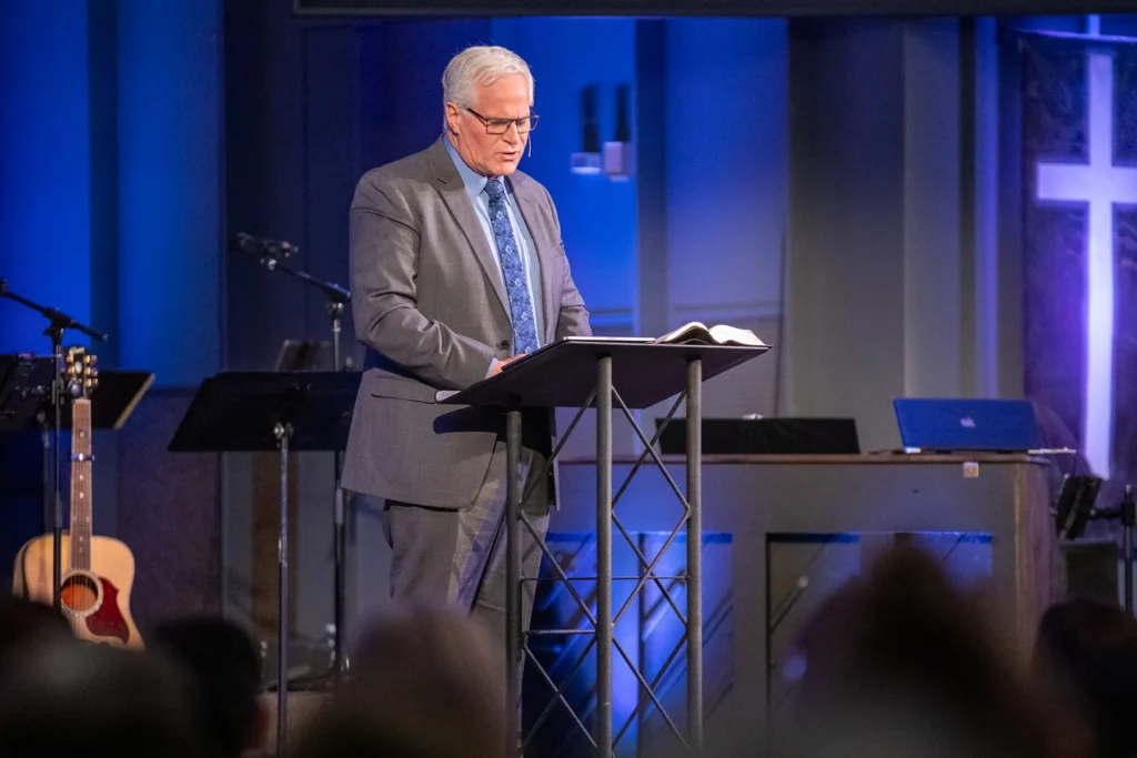 Norm Millar preaching on the stage at Redemption Bible Chapel