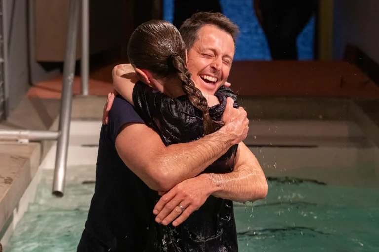 A girl being hugged by father after being baptized
