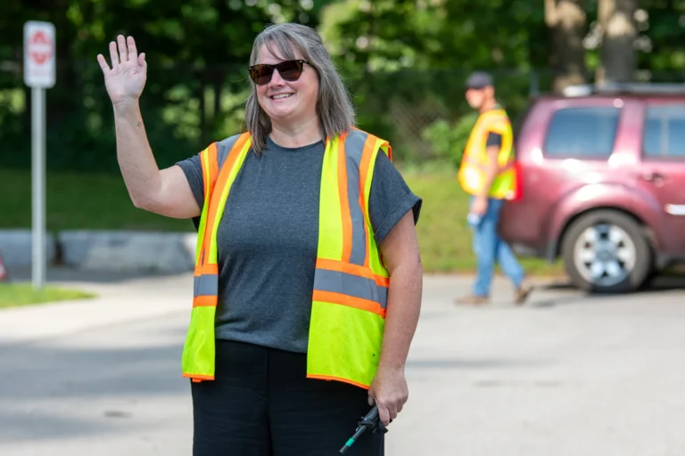 Parking lot volunteer waving to people as they come into the parking lot at Redemption