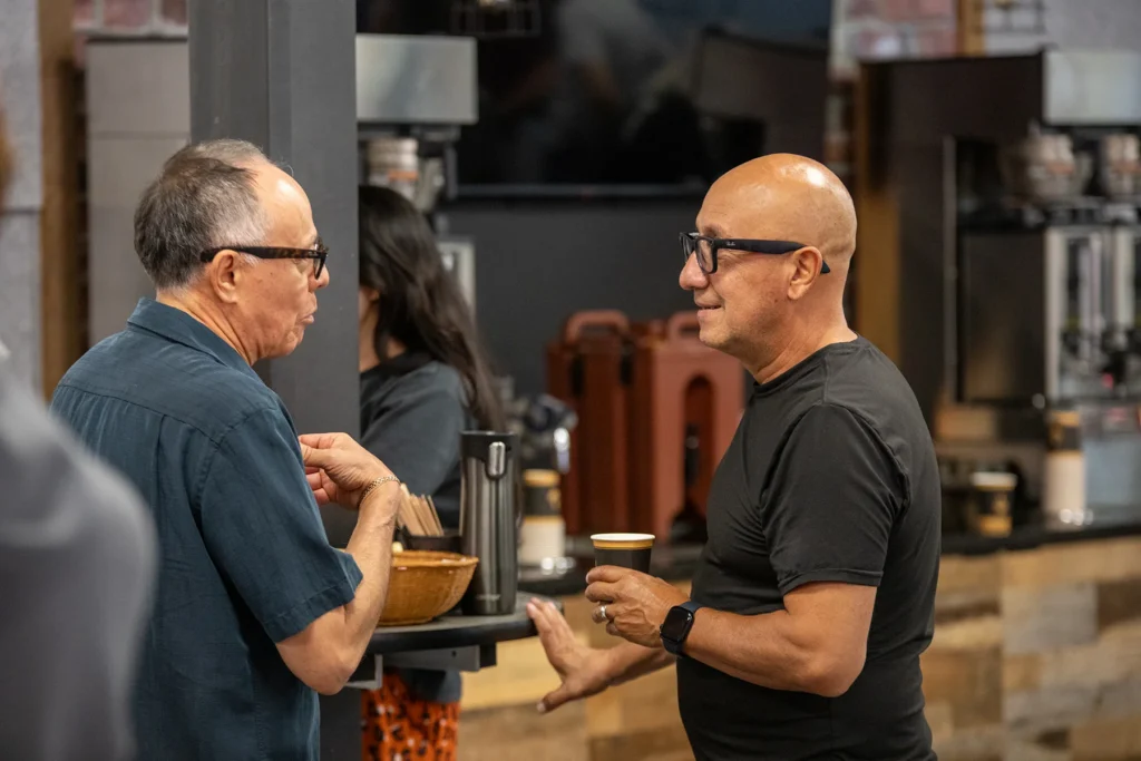 Two members drinking coffee together and chatting after service