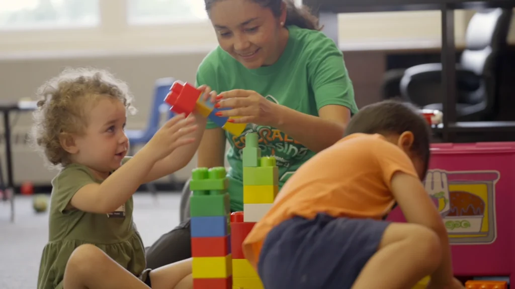 Young child playing with blocks in the nursery with volunteers