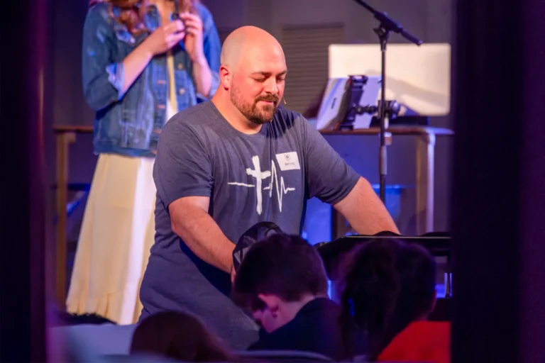 Jeremy, youth leader kneeling on stage praying for youth